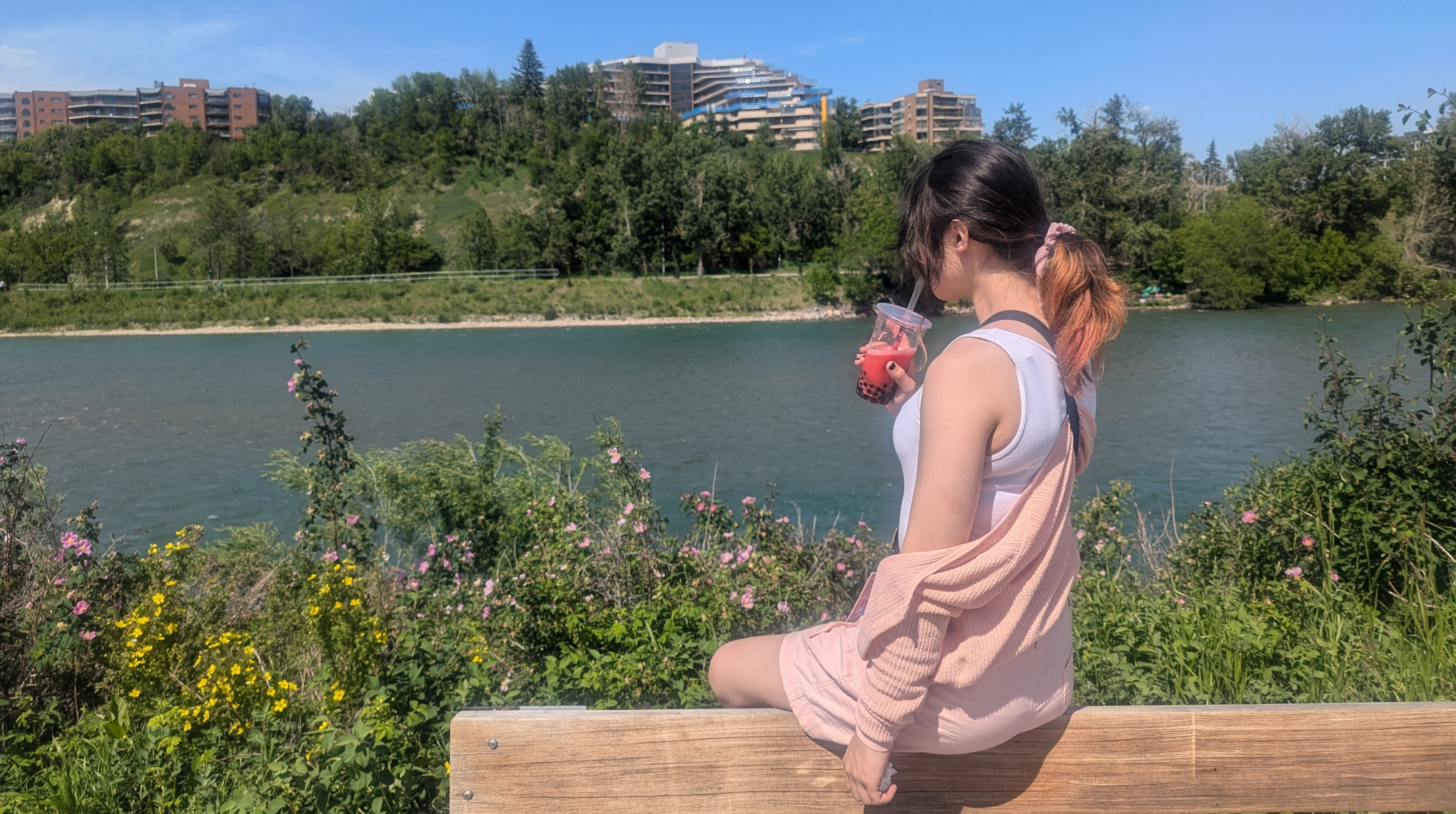 Cailey( @caillazy) sitting on a wooden fence and looking over the river, pondering.